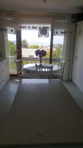 a living room with a table and chairs and a window at Şifne yalı'da 4 oda 9kisi yatak kapasite manzaralı in Cesme
