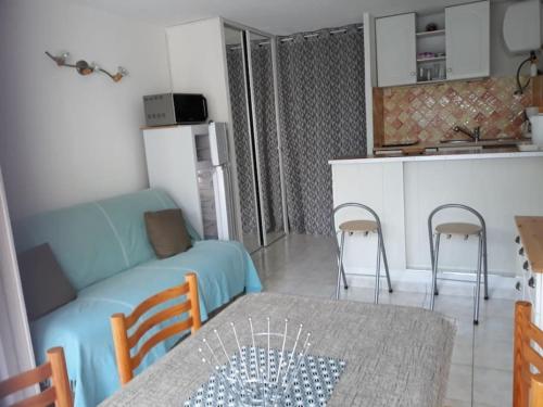 Il dispose d'une cuisine et d'un salon avec un canapé et une table. dans l'établissement Studio Cabine 4 pers Cap d'Agde avec loggia, au Cap d'Agde