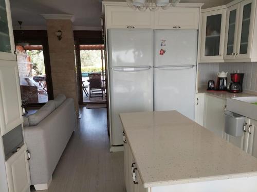 a kitchen with a couch and a white refrigerator at Şifne yalı'da 4 oda 9kisi yatak kapasite manzaralı in Cesme