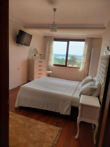 a bedroom with a bed and a dresser and a window at Şifne yalı'da 4 oda 9kisi yatak kapasite manzaralı in Cesme