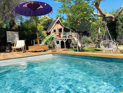 - une piscine avec un parasol et une maison dans l'établissement Villa Exotica et belle cabane en bois idéal famille, à Roquefort-les-Pins