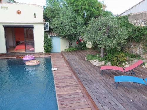 une arrière-cour avec une piscine et une terrasse en bois dans l'établissement Charmante villa avec piscine tout près de l'étang., à Sète