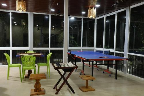 a ping pong table and chairs in a room with windows at The Kille Torna Resort in Pune