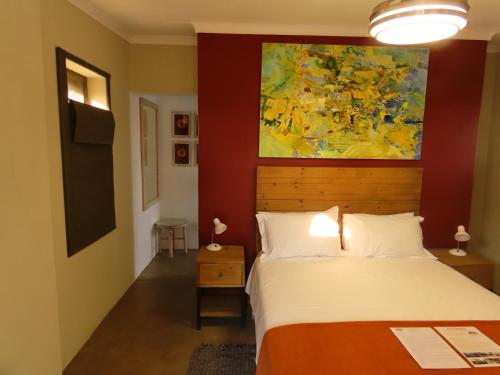 a bedroom with a bed and a painting on the wall at Sunset Lodge & Safaris in Guernsey Nature Reserve
