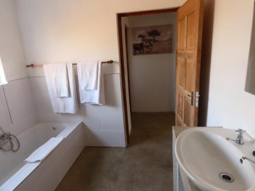 a white bathroom with a tub and a sink at Sunset Lodge & Safaris in Guernsey Nature Reserve