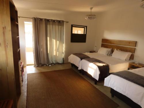 a hotel room with two beds and a window at Sunset Lodge & Safaris in Guernsey Nature Reserve