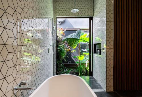 e bagno con vasca e grande specchio. di Villa Catherine - 3BR Lilyfield a Sydney