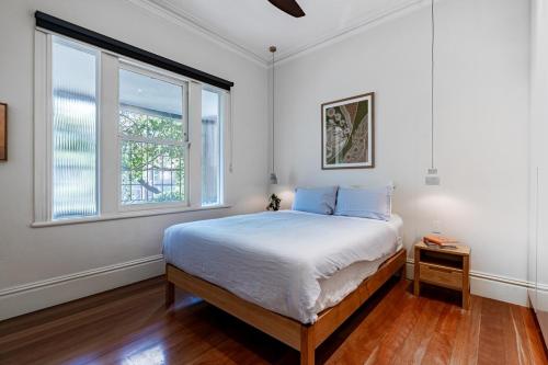 una camera da letto bianca con un letto e una finestra di Villa Catherine - 3BR Lilyfield a Sydney