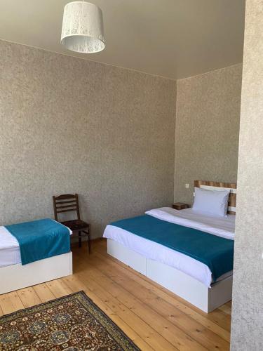a bedroom with two beds and a chair at Guest house LEGIANA Kazbegi in Stepantsminda