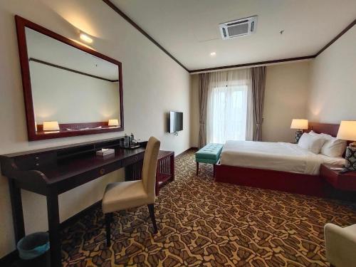 a hotel room with a bed and a desk with a mirror at Riviera Suites Melaka in Melaka