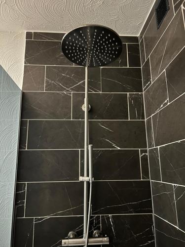 a shower with a black tiled wall with a fan at Cacele - La croisette 5 appartementen en 6 tweepersoonskamers in Vresse-sur-Semois