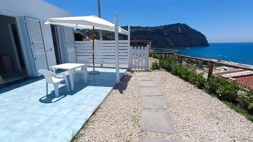 a patio with a table and an umbrella and the ocean at La Dea del Mare in Ischia