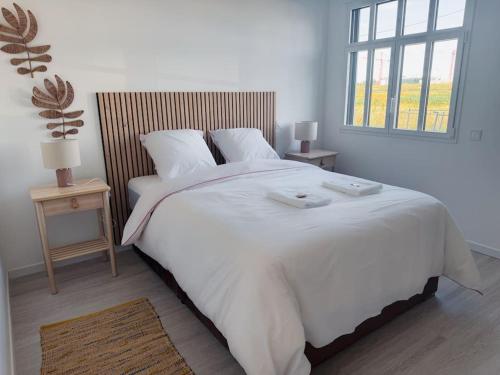 a bedroom with a large white bed with two tables at Somptueux près de Disneyland in Chessy
