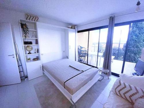 une chambre blanche avec un lit et une grande fenêtre dans l'établissement Studio vue mer à Sant'Ambroggio, Lumio, à Lumio