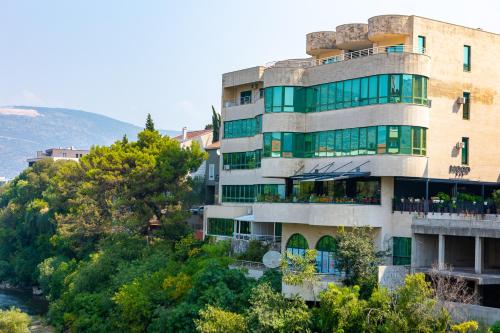 a building on a hill next to a river at River Harmony Apartment in Mostar