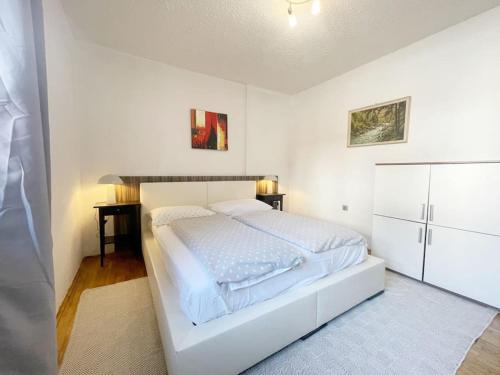 a white bedroom with a bed and a refrigerator at Guest House Šempeter in Šempeter v Savinjski Dolini