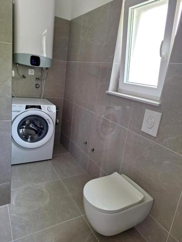 a bathroom with a toilet and a washing machine at Apartment Tanya in Rijeka