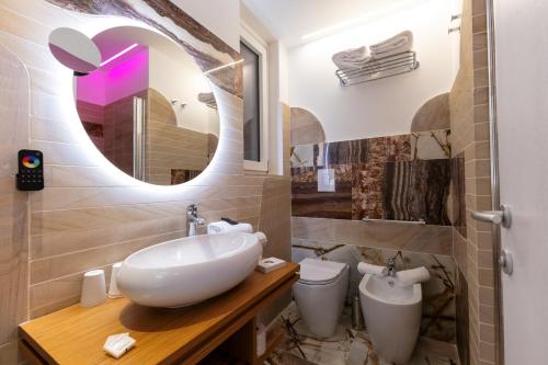 a bathroom with a sink and a toilet and a mirror at Maggiano Boutique Hotel in Peschici