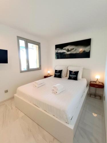 - une chambre blanche avec un grand lit blanc et deux lampes dans l'établissement Le Riva - Standing, Parking, Piscine, Terrasse, à Cassis
