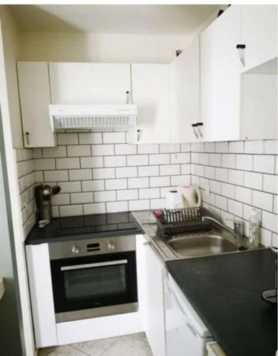 une petite cuisine avec un évier et une cuisinière dans l'établissement Magnifique appartement à 10mins de Disneyland Paris avec Parking, à Bailly-Romainvilliers