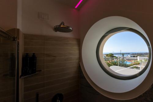 a bathroom with a round mirror and a shower at Maggiano Boutique Hotel in Peschici