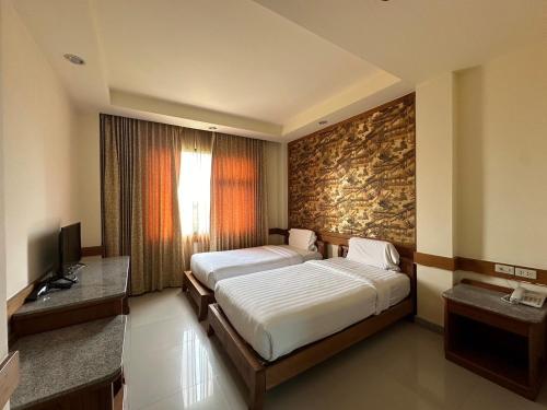 a bedroom with a large bed and a television at โรงแรม อีส จอมเทียน บี in Jomtien Beach