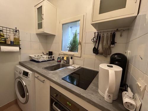 une cuisine avec un évier et une machine à laver dans l'établissement Cosy 1 BDR near Champs-Elysees Opera, à Paris