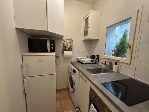 une cuisine avec un réfrigérateur blanc et un évier dans l'établissement Cosy 1 BDR near Champs-Elysees Opera, à Paris