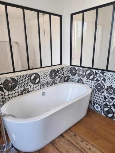 a white bath tub in a bathroom with black and white tiles at La Villa Ausone in Saint-Jean-dʼAngély