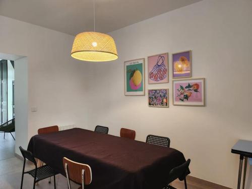 a dining room with a table with chairs and pictures on the wall at La Villa Ausone in Saint-Jean-dʼAngély
