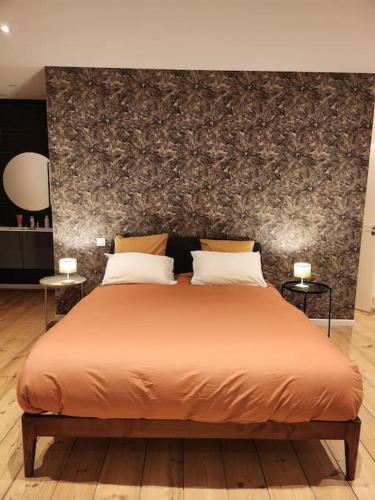 a bedroom with a large orange bed with two tables at La Villa Ausone in Saint-Jean-dʼAngély