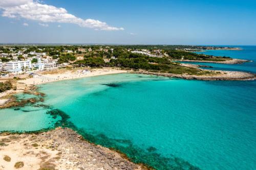 an aerial view of a beach with turquoise water at Montedarena Hotel in Pulsano