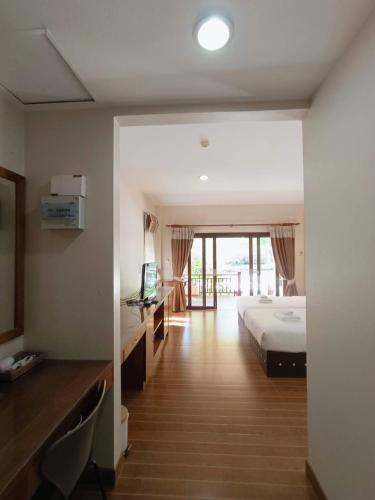 a bedroom with a bed and a desk with a television at Chaithalay Khanom Resort in Ban Phang Phrao