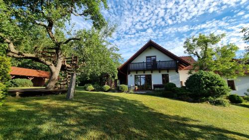 a white house with a tree in the yard at Dům Amelia s vyhřívaným bazénem in Miřetice