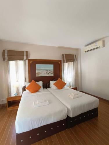 a bedroom with a large white bed with orange pillows at Chaithalay Khanom Resort in Ban Phang Phrao