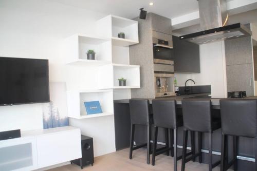 een keuken met een bar met zwarte stoelen en een aanrecht bij Appartement Leon-Rens, op 1 minuut van het strand in Oostende