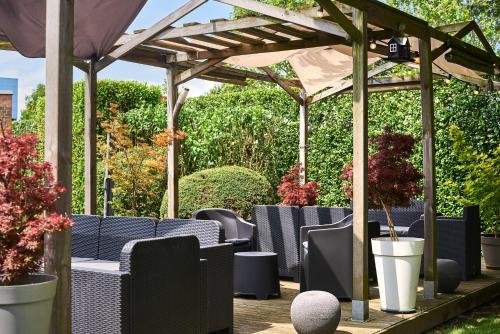 a wooden pergola with blue chairs and potted plants at Hôtel Agena in Faches-Thumesnil