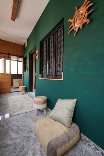 a living room with a green wall with a couch at Aavya Wellness Retreat Center in Rishīkesh