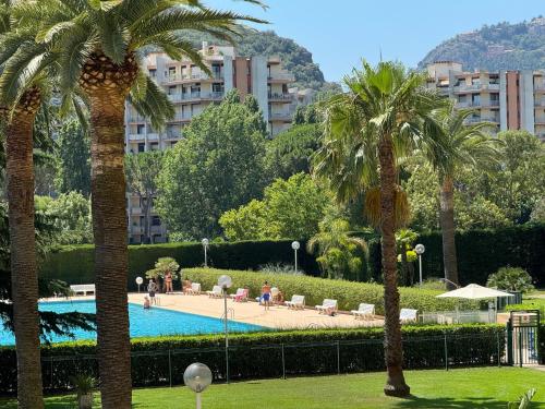 un complexe avec des palmiers et une piscine dans l'établissement My Resid Appart Cannes vue marina et vue montagne, à Mandelieu-la-Napoule