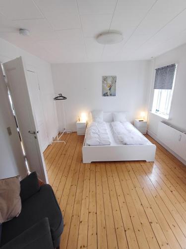 a white bedroom with a bed and a couch at 1 Bedroom Apartment In Frederikshavn City With Free Parking in Frederikshavn