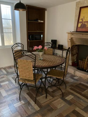 - une table et des chaises dans le salon doté d'une cheminée dans l'établissement Chambre améliorée dans petite maisonnette, Au moulin du bonheur, à Le Bourdet