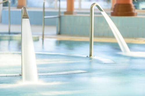 a swimming pool with white poles and water in it at LES TERRASSES DE BORDA*** in Dax