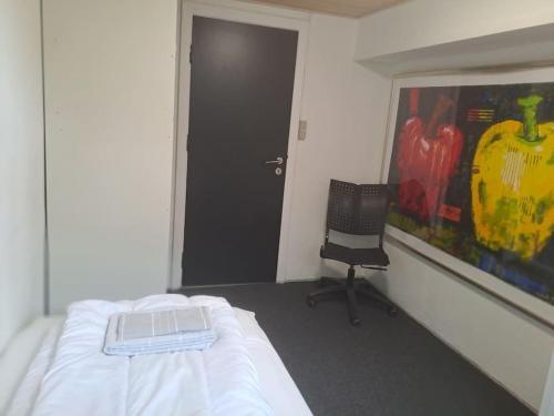 a room with a bed and a chair and a painting at Centralt beliggende hyggeligt byhus med 8 sovepladser 130m2 med pejs in Holstebro