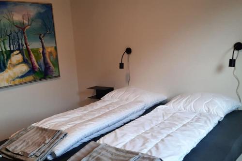 two white beds in a room with a painting on the wall at Centralt beliggende hyggeligt byhus med 8 sovepladser 130m2 med pejs in Holstebro
