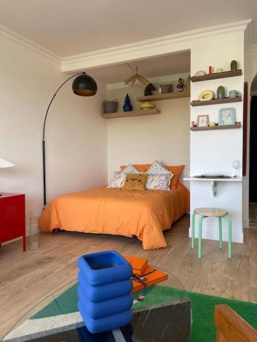 ein Schlafzimmer mit einem orangefarbenen Bett und einem blauen Hocker in der Unterkunft Luxueux Studio Neuf-Balcon-6min Gare-15min Paris in Sartrouville