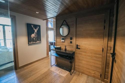 La salle de bains est pourvue d'un lavabo et d'un miroir à côté d'une porte. dans l'établissement Appartement aux pieds des pistes, à Saint-Étienne-de-Tinée