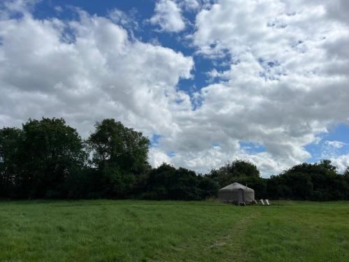 a tent in a field under a cloudy sky at Nordic Glamping at Botswicky - a nature based retreat in Bishopstone