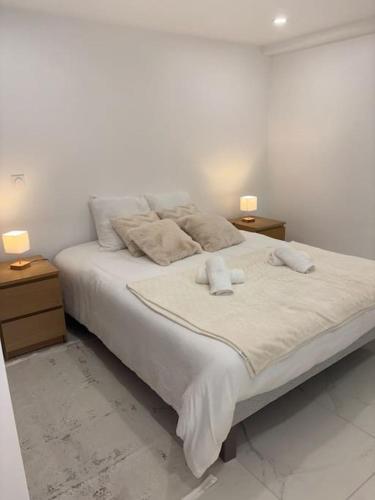 un lit blanc avec deux tables de nuit et deux lampes dessus dans l'établissement Le petit moret, à Joinville-le-Pont