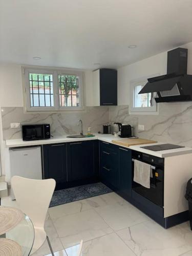 une cuisine avec des armoires bleues et des comptoirs blancs dans l'établissement Le petit moret, à Joinville-le-Pont