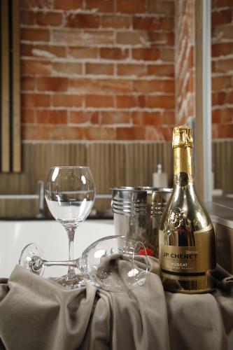 a bottle of wine and a glass on a table at Design Apartment GRAND SPA LUX 4 STAR "MALIBU" Completely PRIVATE Wellness & Spa FREE INCLUDED Jacuzzi & Salt Wall & Fire place & 3D Ceilings & Business WiFi & NETFLIX & LED Lights & Keyless code entry & FULL SMART APP & SECURE 2 Parking place in Ćuprija